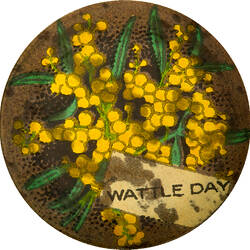 Front of circular badge with wattle design.
