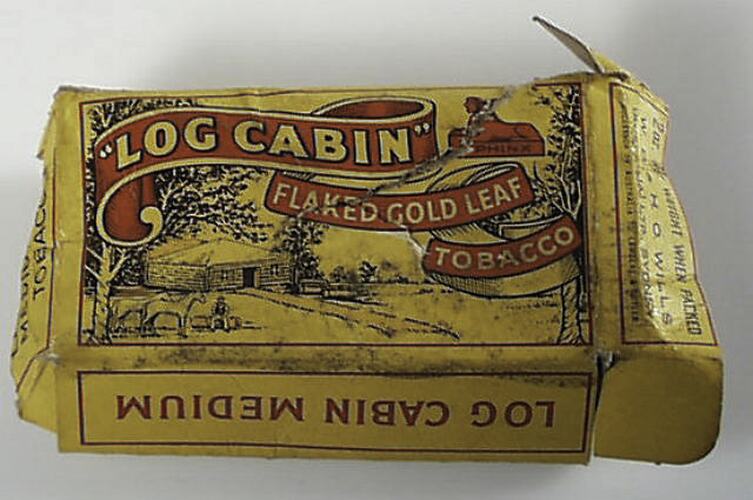 Printed cardboard tobacco box, depciting a log cabin, yellow background with red and black text.