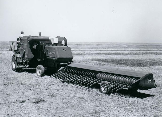 Man driving a header in transport mode with the header being towed behind.