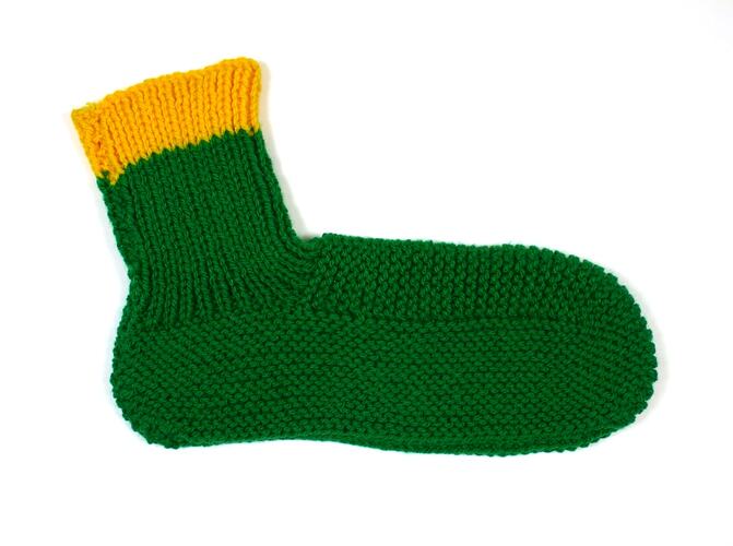 Green woollen bedsock with yellow cuff.
