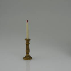 Gold coloured candle stick and white candle, sized for a doll house.