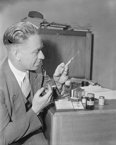 May & Baker Ltd, Scientist Holding Two Hypodermic Needles, Melbourne, Victoria, 1953
