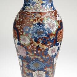 Ornate colourful vase, slightly tapered body with a small lip. Off-white base with peonies, cherry blossoms, chrysanthemums, fans and butterflies.