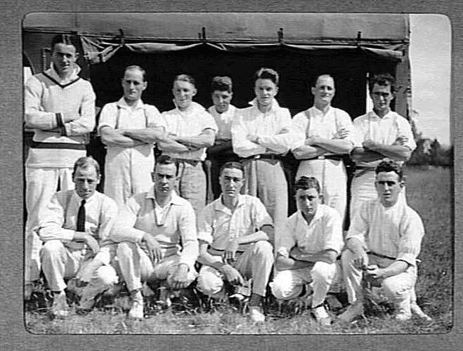 Cricket team of twelve men posing in front of a truck.