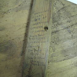 Close-up of section of wood with text written vertically down.