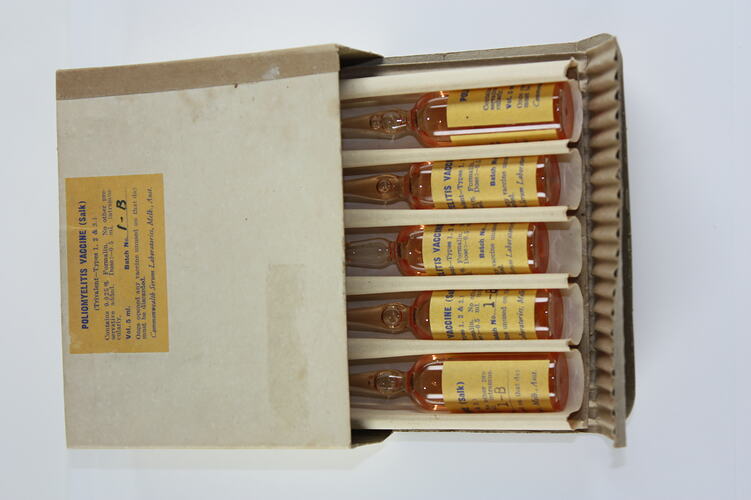 Box of five glass ampoules with amber coloured solution. Each has yellow label.