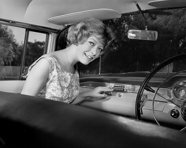 Woman seated in front seat of car.