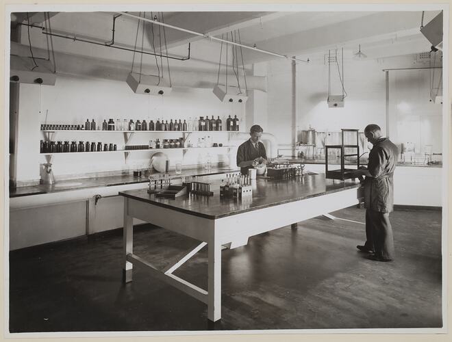 Two men at a table working with chemicals.