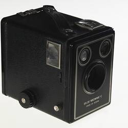 Black box-shaped camera, central lens, two circles at top. Three quarter view. Window on side.