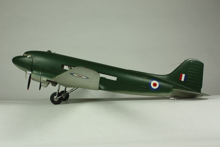 Dark green two propeller aeroplane model with two wheels and painted red, white, blue flag and roundles.