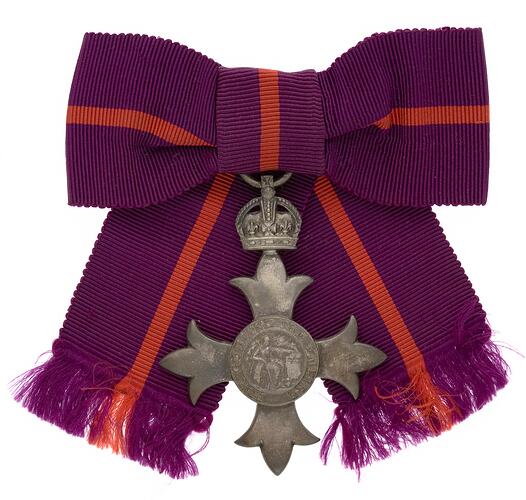 Metal badge with crown attached to purple and red ribbon.
