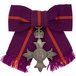 Metal badge with crown attached to purple and red ribbon.