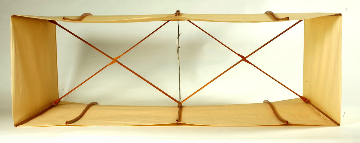Box kite with two square sections made of cream fabric with wood and metal frame.