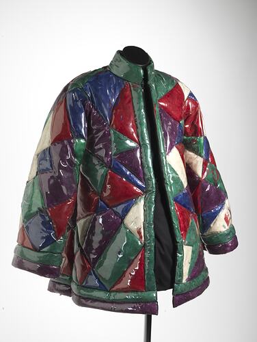 Quilted geometric plastic jacket filled with coloured feathers. The quilted sections are triangular.