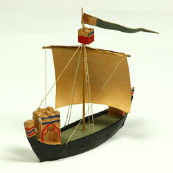 Three quarter view of ship with black hull and painted sail.