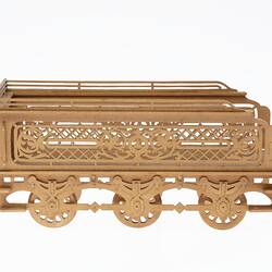 Wooden tender model made of fretwork. Has three pairs of moving wheels. Right profile.