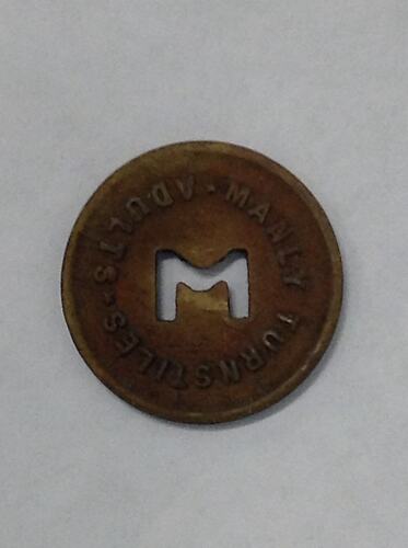 Round coin with M cut out of centre.