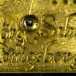Decorative table clock, square gilded brass case. Detail of engraving.