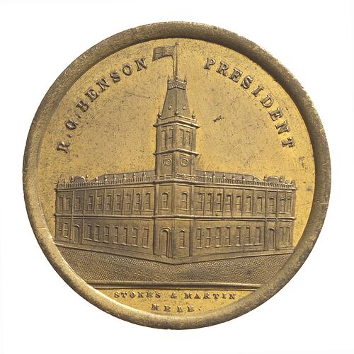 Medal with Malvern Town Hall. View of two-storey corner building with tower. Text above and below.