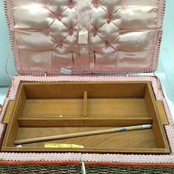 Sewing box with single pink stripe around the woven cane exterior. Pink satin interior edged with ribbon.