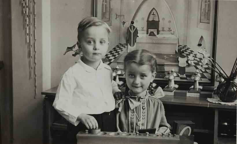 Boy and girl in indoor setting with a game and mirror in background.