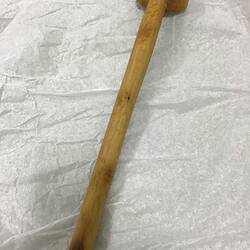 Back of wooden spoon with long handle, small bowl shape at tip.