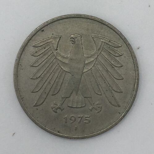 Round silver coin featuring bird with outstretched wings. Date below.