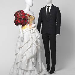 White wedding dress with red shoulder detail and black suit with white shirt, black tie.