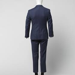 Back view of blue suit jacket and pants with thin red square check pattern. Branded brown plastic buttons at cuffs.