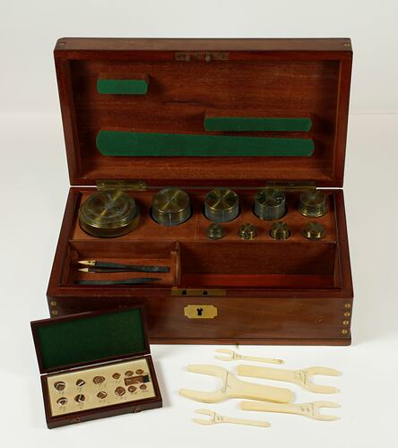 Standard gilt brass weights shown in an open box. Platinum wire weights in smaller wooden box in front.