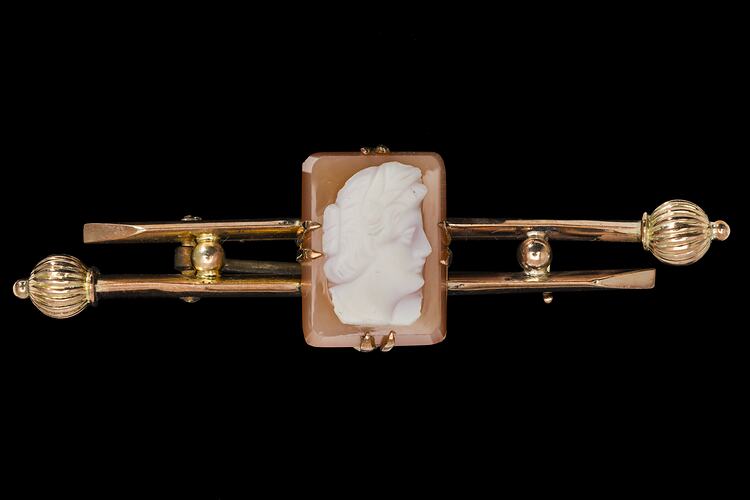 Double gold bar with central rectangular reddish-brown and white female cameo bust facing right.