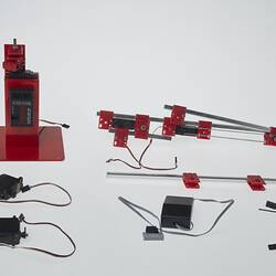 Red and black plastic components with cables that make up a toy robotic arm.