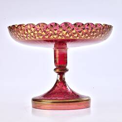 Red glass base/stand of epergne. Shaped like one piece plate on stand. Gilded decoration.