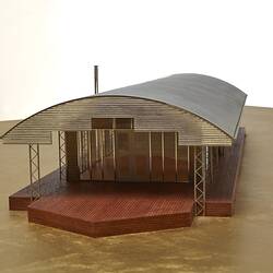 Model of a house with an arched roof, corrugated iron and wide expanses of glass.