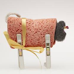 Toy sheep made from folded orange dishwashing sponge, steel wool ball, matches, white pegs.