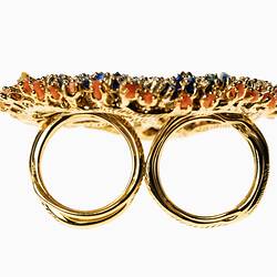 Profile of large-scale, two-fingered gold ring set with multicoloured microplastics.