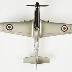 Top view if silver model plane. Blue, white, red roundel on wings. Front has black four blade propeller.