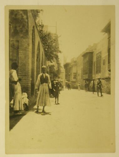 Street scene with buildings, two Iraqi men in foreground.