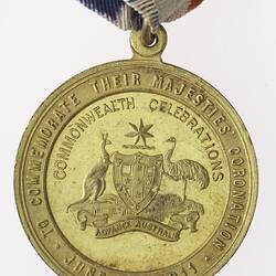 Round gold coloured medal with Australian coat of arms and text, with blue, white and red ribbon.