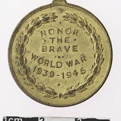 Gold coloured medal with text framed by wreath, reading "HONOR THE BRAVE. WORLD WAR 1939-1945."