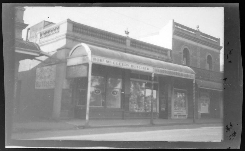 Row of window-fronted brick Buildings with curved metal veranda roof.