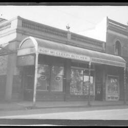 Row of window-fronted brick Buildings with curved metal veranda roof.