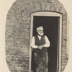 Man standing in doorway of brick building.