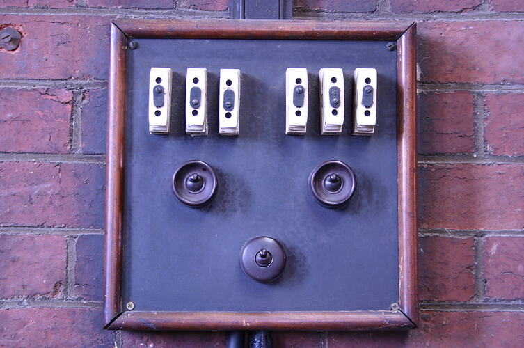 Bakelite light switches and old fuses mounted on a brick wall.