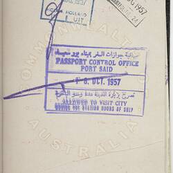 White passport page with blue, purple and black stamps.