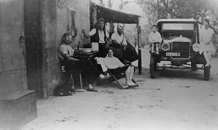 A group of people outside a hessian and bark hut belonging to a Murray River fisherman