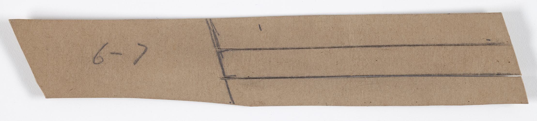 Brown colored cardboard rectangle with pencil notations.