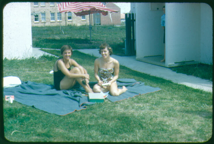 Two women in swimsuits sitting on towels