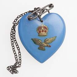 Blue heart pendant with gold crown and bird. Hangs from metal chain and safety pin.