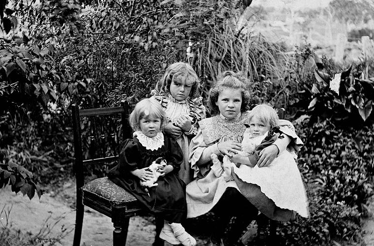 Four children sitting outside holding their pet guinea pigs.